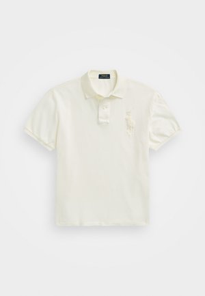 Polo creme com gola de três botões, mangas curtas e um logótipo bordado no lado esquerdo do peito. Tecido de algodão suave e liso.