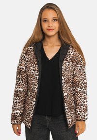 Doudoune imprimé léopard, motif marron et crème, capuche et bordures noires, texture matelassée, associée à un haut noir et un jean foncé.