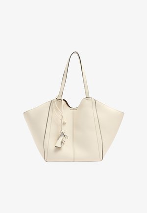 Kremowa torba na ramię ze skóry z szerokimi bokami, podwójnymi paskami na ramię oraz ozdobnym breloczkiem i frędzlem zawieszonym na jednym pasku.