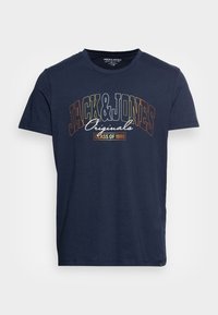 Námorně modré bavlněné tričko s krátkým rukávem. Obsahuje grafický potisk s vícerozbarveným textem: "JACK & JONES Originals TŘÍDA 1990."