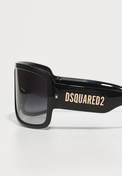 Mustad ülekaalulised prillid tumedate gradientobjektiividega, mille küljes on silmapaistev kuldne "DSQUARED2" logo.