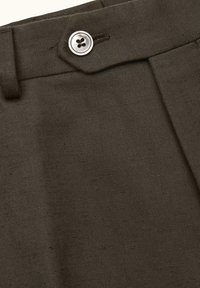 Pantaloni verde scuro con una texture liscia, dotati di un unico bottone argento in vita e un design con pieghe sul davanti.