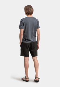 T-shirt grigio a maniche corte, pantaloni corti neri con tasche curvate e sandali marroni. Vestibilità rilassata con superficie liscia e design minimalista.