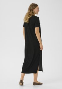 Black maxi dress with short sleeves, featuring side slits for ease of movement, made from a soft, lightweight fabric. Simple design details.