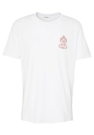 T-shirt en coton blanc avec un motif de flamme rouge, associé à un jean bleu clair et des baskets blanches, présentant une coupe décontractée et un design minimaliste.