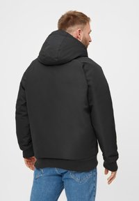 Černá mikina s kapucí, hladkým povrchem, elastickými manžetami a volným střihem. Navržena s jednoduchou siluetou, vhodná pro každodenní nošení.