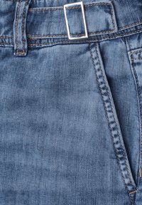 Close-up of blue denim jeans with metal rectangular belt buckle and visible topstitching around the waistband and pocket.