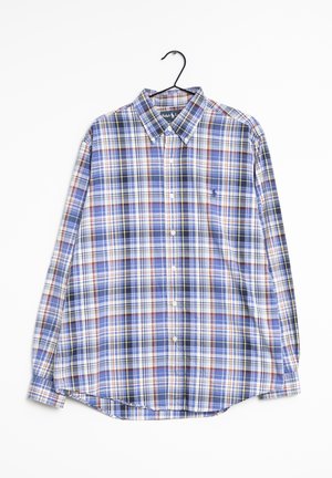 Koszula na długi rękaw z guzikiem, w niebiesko-biało-czerwoną kratę, wisząca na czarnym wieszaku.