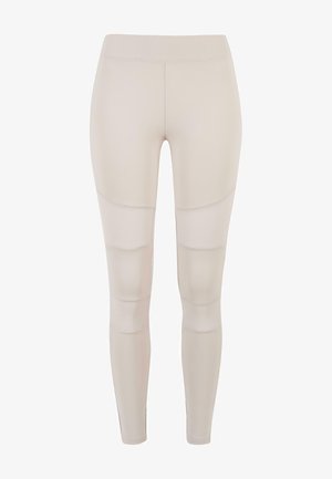Leggings de sport beiges avec une coupe ajustée, dotés d'accents en maille et d'une texture lisse. Pas de marque ni de motifs visibles.