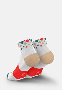 Weiße Knöchelsocken mit roten Fersen und Zehen, die ein mehrfarbiges geometrisches Muster am Bündchen in Türkis, Rot und Beige aufweisen. Glatte Textur.