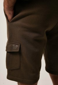 Braune Baumwollstoffshorts mit einer seitlichen Cargo-Tasche mit Klappe und Logo-Detail, glatter Textur und einem bequemen Sitz.