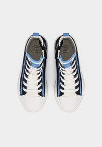 Para czarnych i niebieskich sneakersów za kostkę z białymi sznurowadłami i podeszwami, widzianych z góry na jasnym tle.