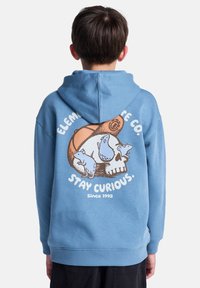 Blå hoodie med en grafik av ett skalle och tre djur. Har en känguruficka, ribbade ärmar och nederkant, tillverkad av mjukt, texturerat tyg.