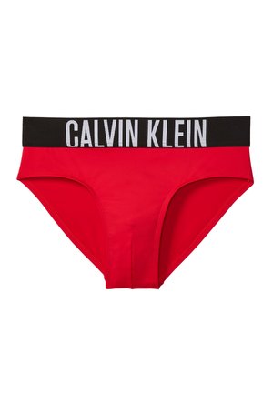 Rote Herren-Slips mit einem breiten schwarzen Bund, auf dem vorne in Weiß "Calvin Klein" steht.
