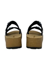 Sandali platform neri con cinturini regolabili, suole simili al sughero, base testurizzata e superficie interna liscia, caratterizzati da dettagli hardware minimi.