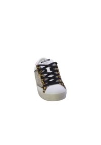 Sneaker bianco con lacci neri, dettagli in stampa leopardata e pannello laterale argentato scintillante. Punta arrotondata e soletta testurizzata.