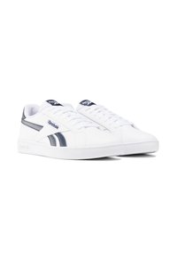Baskets blanches avec des accents marine, tige en cuir, design à lacets, col rembourré et semelle en caoutchouc avec le logo Reebok sur la languette et le côté.
