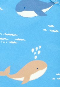 Tela azul con dos ilustraciones de ballenas; una gris y una beige, rodeadas de nubes blancas y salpicaduras de agua.