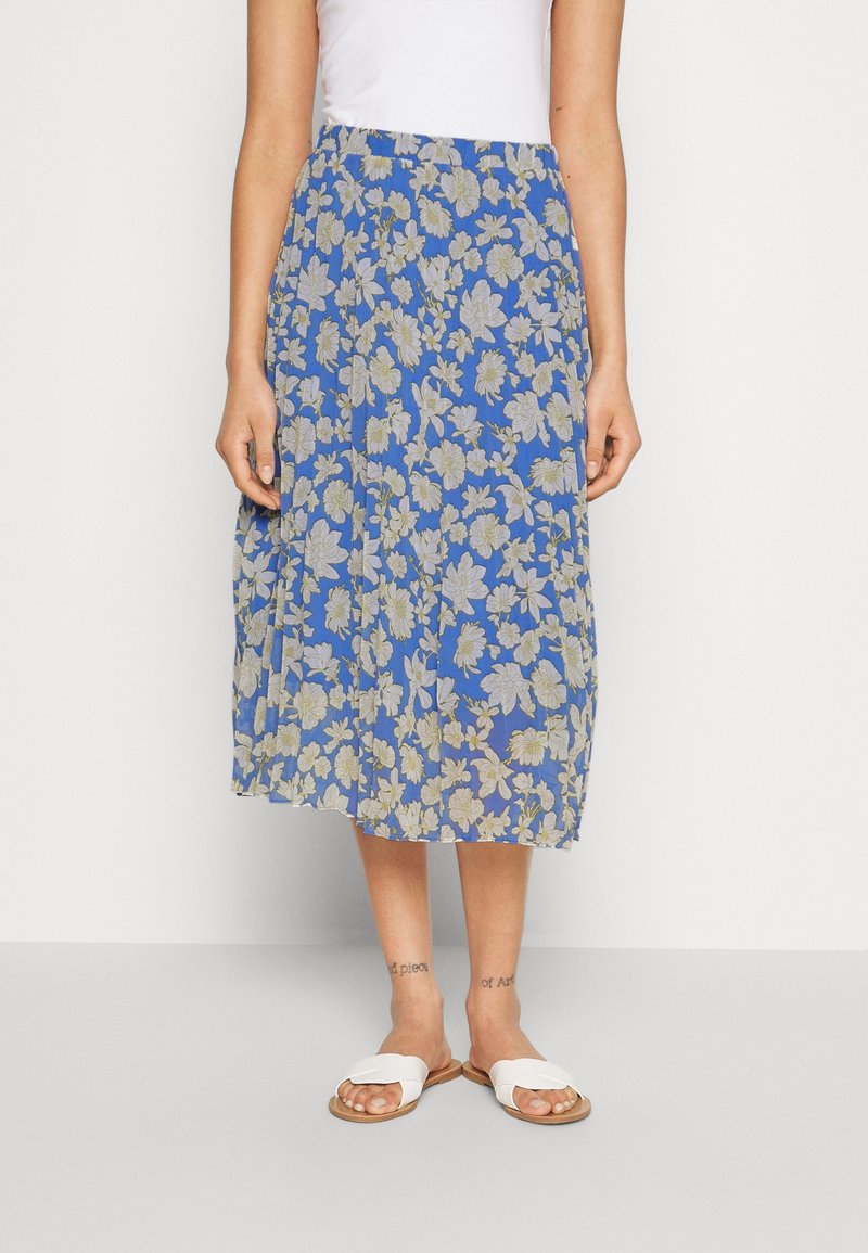 Gonna midi floreale blu, con motivi floreali chiari, vita elastica e tessuto leggero. Indossata con sandali bianchi flat.