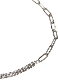 Silver chainhalsband med växlande länkar och en rad rektangulära klara kristaller längs ena sidan, vilket skapar en kontrast i designelement.