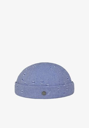 Blue denim style beanie hat with rolled-up brim and distressed holes, featuring a small round metal logo badge on the front.