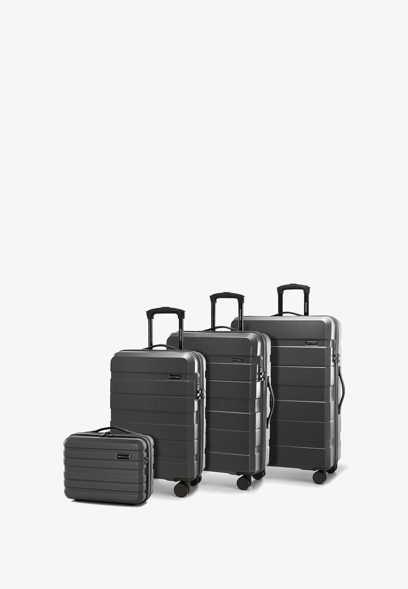 Čtyři šedé tvrdé kufry různých velikostí, které mají horizontální drážky, teleskopické rukojeti a hladká kola pro snadnou mobilitu.