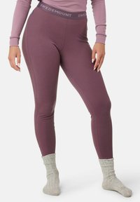Fioletowe legginsy w prążki z logo na pasku, zestawione z jasnoszarymi wełnianymi skarpetkami. Design jest dopasowany do sylwetki i ma gładką teksturę.