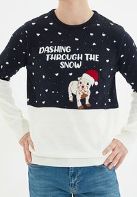 Navyblauer und weißer Strickpullover mit dem Schriftzug "DASHING THROUGH THE SNOW", einem Bulldoggen im Weihnachtsmannhut und Schneeflockenmuster.