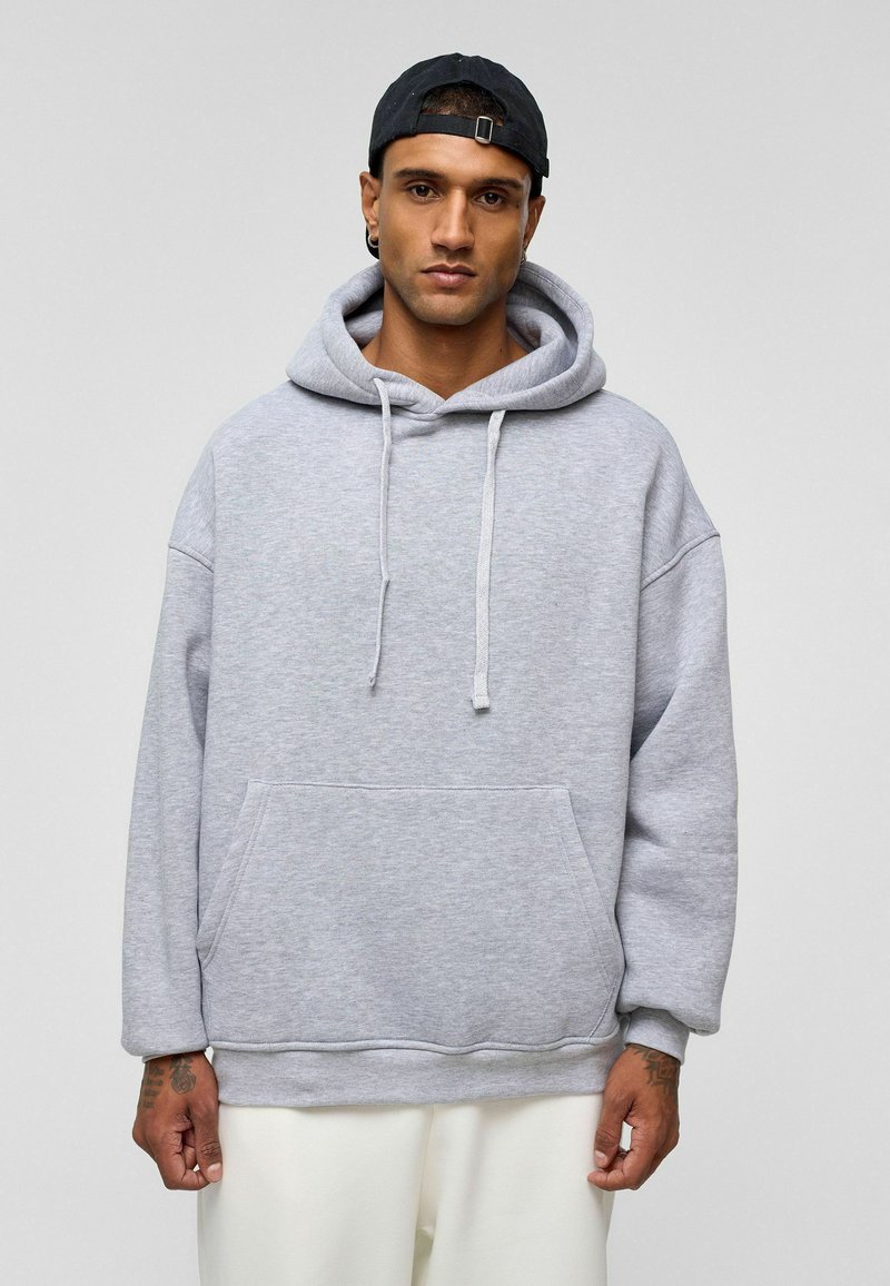 Lichtgrijze hoodie met een voorzak, losse pasvorm en koordjes. Heeft geribbelde manchetten en zoom, gemaakt van zachte stof.