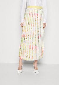 Faltenrock in Midi-Länge mit floralen Mustern in Pastellfarben, ausgestattet mit einem gelben Bund. Das Material wirkt leicht und fließend.