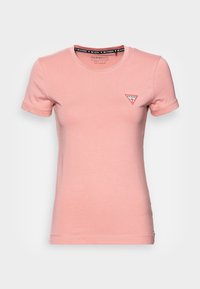 T-shirt aderente rosa in cotone morbido, con collo rotondo e maniche corte. Piccolo logo triangolare sul lato sinistro del petto in rosso e bianco.