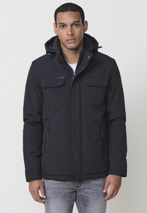 Chaqueta negra con capucha, con cremallera frontal, dos bolsillos en el pecho y cremalleras laterales. Hecha de un tejido texturizado, con un diseño ajustado y cierres seguros.