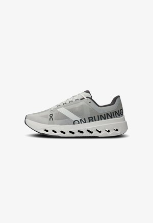 Hellgraue Laufschuhe mit einem Obermaterial aus Mesh, grafischen Details, runder Zehenpartie, gepolstertem Kragen und einer dickeren, skulptierten weißen Sohle mit Belüftungsöffnungen.
