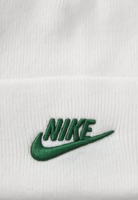 Balta bemine su raukšlėta tekstūra, priekyje esantis žalias išsiuvinėjimas su Nike logotipu.