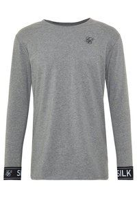 Graues langärmeliges Shirt aus weichem Material, mit Rundhalsausschnitt, einem kleinen schwarzen Logo auf der Brust und kontrastierenden schwarzen Bündchen mit dem Text "SILK".