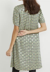 Grön klänning med ett geometriskt triangelmönster i marinblått och guld. Korta puffärmar, en avslappnad passform och en sidoklaffdetalj.