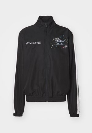 Sort lynlåstrøje lavet af glat stof med hvide skulderstriber, "Carlo Colucci" logo og teksten "MCMLXXVIII" i hvid.