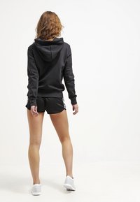 Zwarte hoodie met een gestructureerde afwerking en bijpassende zwarte shorts. Bevat witte gestreepte accenten op de shorts. Eenvoudig atletisch ontwerp.