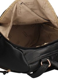 Zwarte handtas van getextureerd leer met een ritssluiting. Het interieur is voorzien van een lichtbruine voering met herhaalde "pierre cardin"-branding.