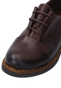 Brauner Schnürschuh aus Leder mit rundem Zehenbereich, strukturierter Oberfläche, kontrastierenden Nähten und einer robusten Gummisohle.