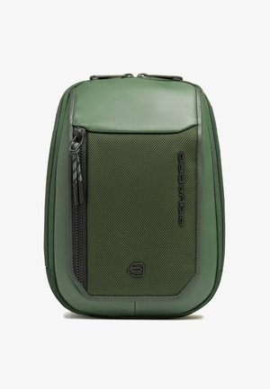 Pochette verticale compacte verte avec poche avant zippée, panneau en tissu texturé et logo "Piquadro" sur le côté droit.