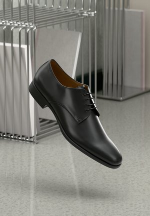 Chaussure habillée en cuir noir avec une finition lisse, bout arrondi, design à lacets et petit talon, placée sur un fond moderne et minimaliste.