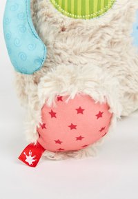 Plush toy leg with beige fur, blue fabric arm, green striped fabric, and pink fabric foot with red star pattern and red tag.