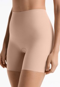 Bezszwowe, kształtujące szorty w odcieniu nude, wykonane z gładkiego, elastycznego materiału, z elastycznym paskiem w talii i małym otworem na środku.
