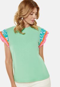 Tricou verde mentă cu mâneci ondulate în nuanțe de teal și roz, având guler rotund și o croială lejeră. Textură netedă.