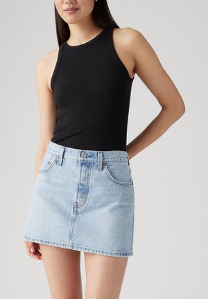 Svart ribbad linne med hög halsringning, ihopparat med en ljusblå denim minikjol med fickor och knappstängning framtill.