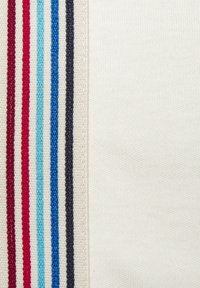 Gestreifter Stoff mit roten, hellblauen, dunkelblauen und schwarzen Streifen auf einer Seite, im Kontrast zu einem glatten weißen Stoff auf der anderen Seite.