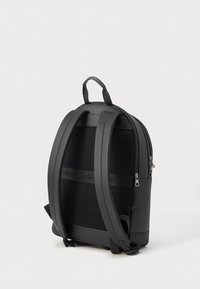 Čierny batoh so štruktúrovaným povrchom, polstrovaným sieťovaným zadným dielom, nastaviteľnými popruhmi a dvojitým zipsom. Ozdobený so značkovými detailmi.