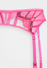 Roze mesh jarretelgordel met geometrisch ontwerp, voorzien van kanten accenten, satijnen banden en hardware in goudkleur. Inclusief decoratieve franjes.