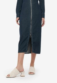 Denim zip jurk met lange mouwen en een split aan de voorkant. Gecombineerd met crèmekleurige instapsandalen met een textuurpatroon en blokhak.